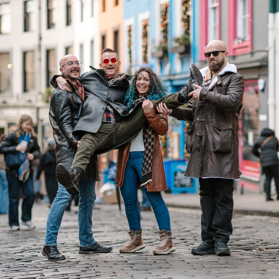 Friends enjoying a vacation photography session on Victoria Street in Edinburgh, Scotland