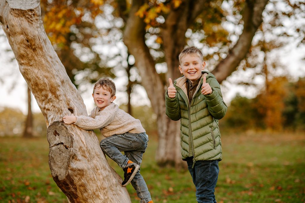 Two children playing beside a tree during an autumn family photoshoot at Dalkeith Country Park
