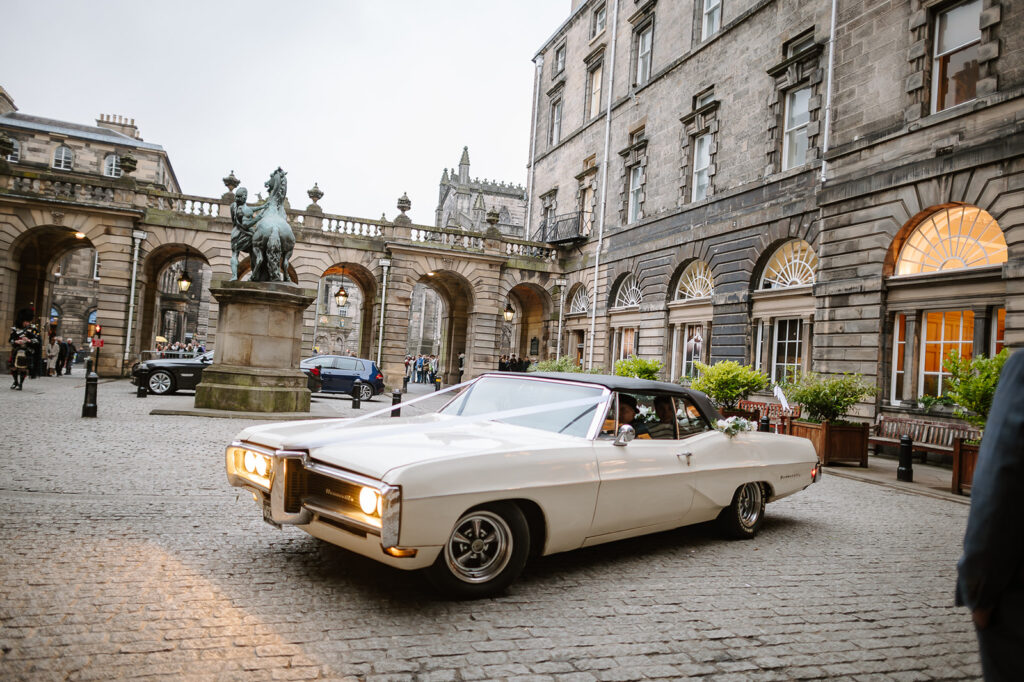 White vintage wedding car arriving outside Edinburgh City Chambers
