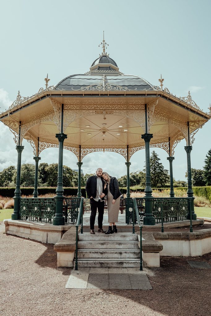 Jenna and Mike standing at the Saughton Park bandstand during their engagement photoshoot