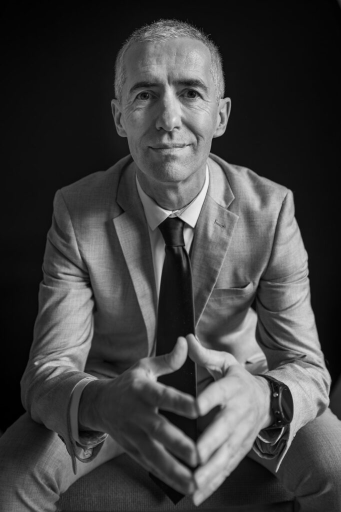 Black-and-white business headshot photographed against a dark background